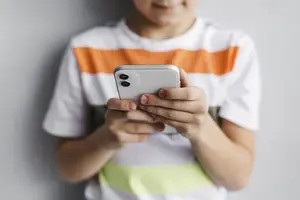 Criança com celular e os problemas do uso excessivo das telas (Foto: Reprodução)
