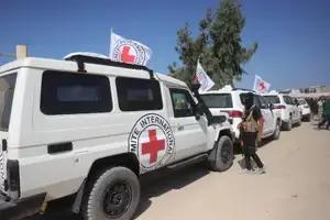 Membro do Hamas ao lado de veículos da Cruz Vermelha, que carregam reféns de volta para Israel (Foto: Reprodução | Bashar Taleb/AFP)