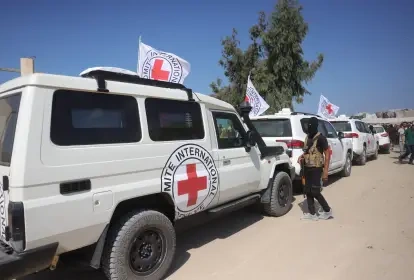 Membro do Hamas ao lado de veículos da Cruz Vermelha, que carregam reféns de volta para Israel