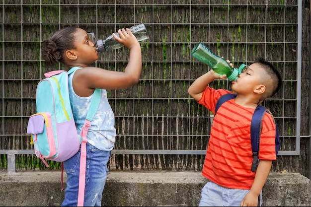Crianças bebendo água na porta da escola