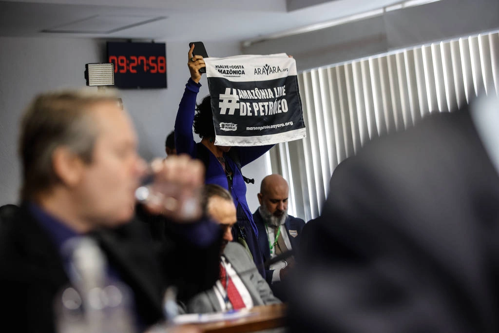 Mulher segura faixa com a frase "Amazônia livre de petróleo" durante participação de Marina Silva na Comissão de Infraestrutura do Senado