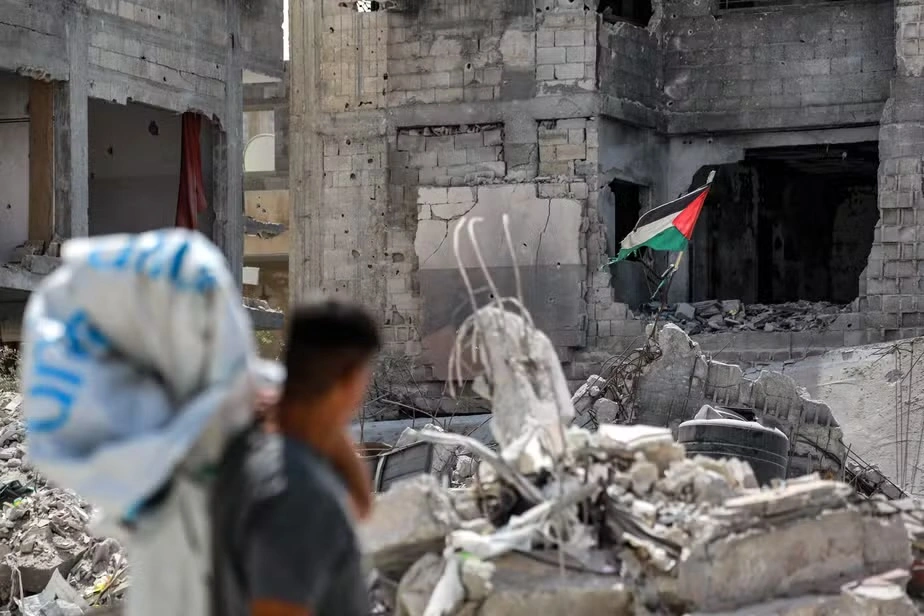 Homem observa bandeira da Palestina hasteada sobre as ruínas em Khan Yunis, no sul da Faixa de Gaza
