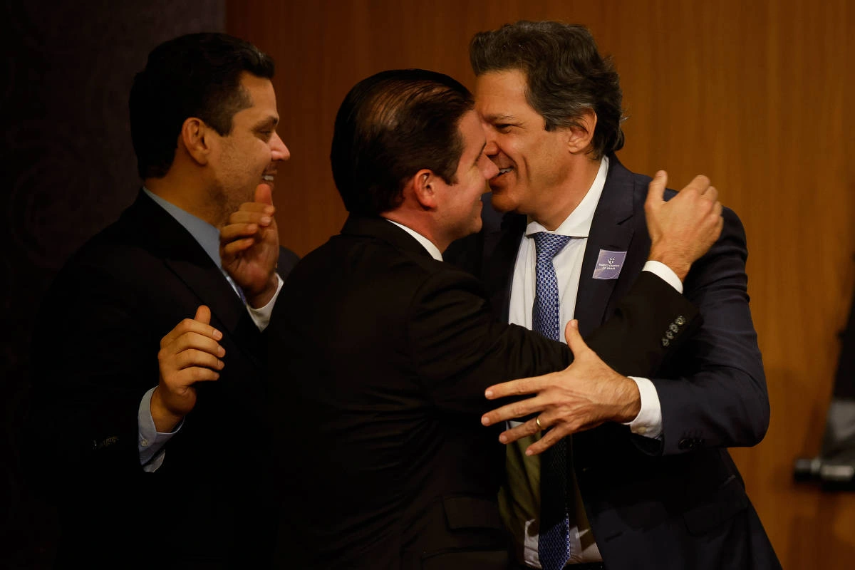 Os presidentes da Câmara dos Deputados e do Senado Federal, deputado Hugo Motta (C) e senador Davi Alcolumbre (E), abraçam o ministro Fernando Haddad (Fazenda) (D)
