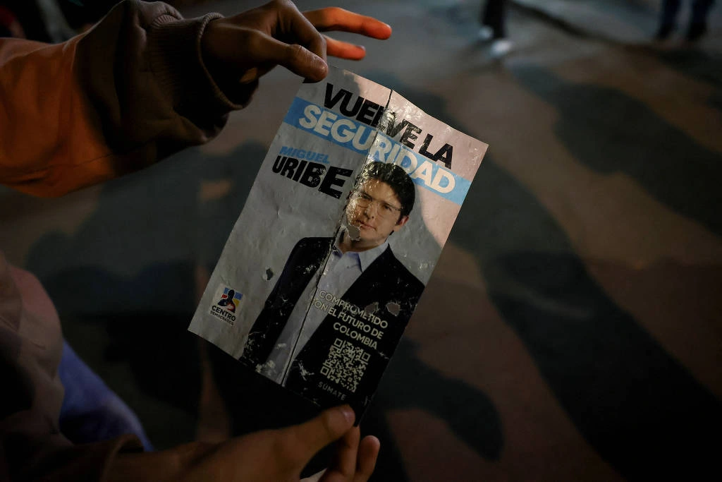 Pessoa segura cartaz de campanha onde senador colombiano Miguel Uribe, do partido de oposição Centro Democrático, foi baleado em Bogotá