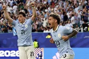 Dois jogadores da seleção uruguaia vestindo camisa azul clara e calção branco comemoram gol. Um levanta os braços e o outro grita com punhos cerrados. Torcida ao fundo aplaude em arquibancada cheia. Vinãs e Maxi Araújo celebram o gol de empate do Uruguai na partida em Miami pela Copa do Mundo (Foto: Reuters)