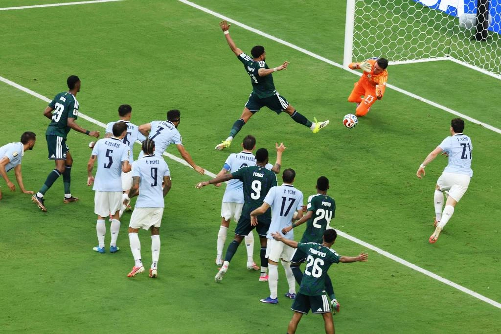 Goleiro de uniforme laranja salta para defender chute próximo ao gol enquanto jogadores de duas equipes observam na área. Abdulelah Al-Amri aproveitou rebote de Muslera para fazer o gol da Arábia Saudita